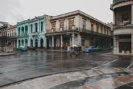 A vintage street scene with classic cars and old buildings in Havana, Cuba after rain.